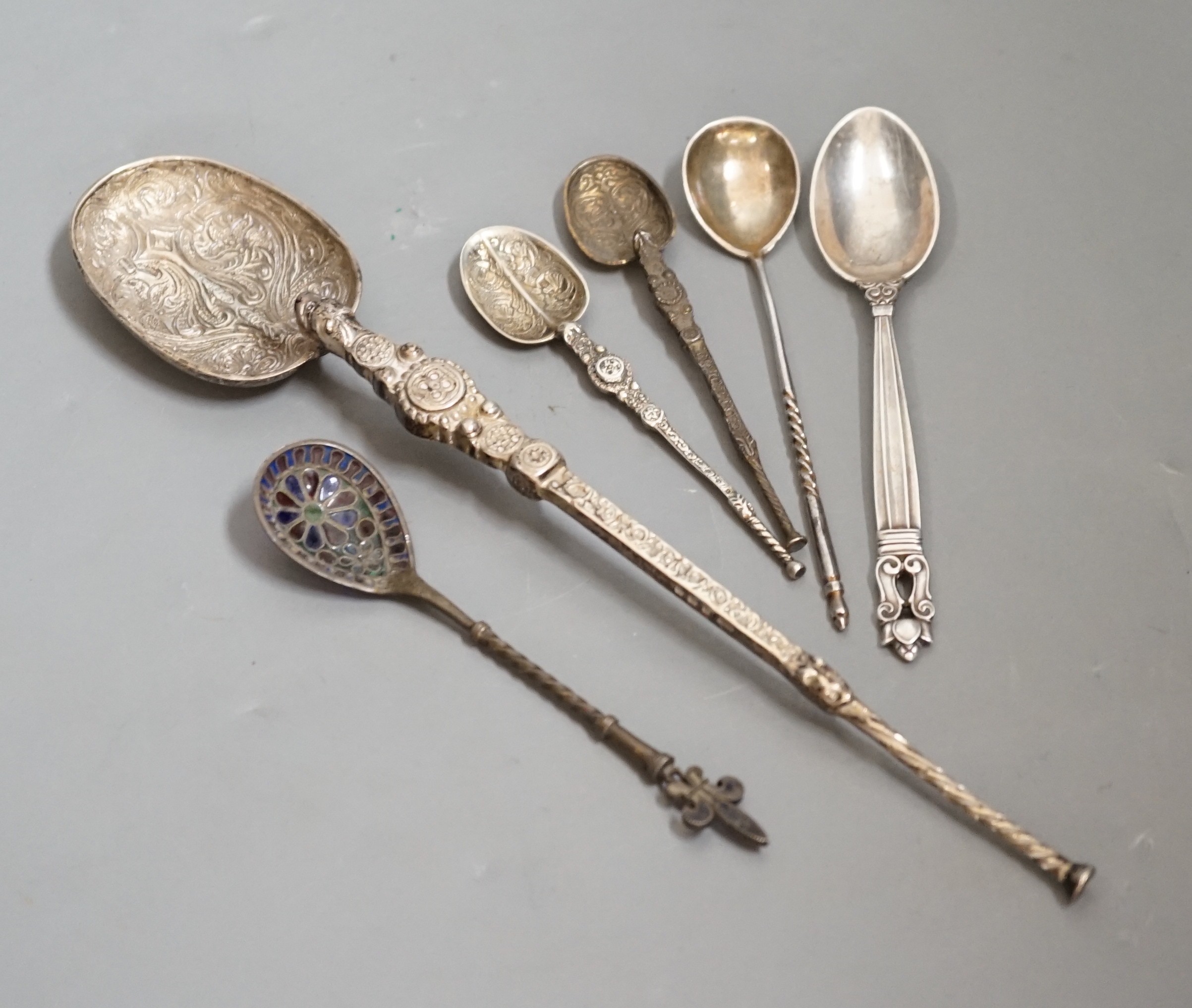 A 1930's silver replica of The Anointing spoon, 24.7cm, two similar smaller spoons, a Georg Jensen spoon, an Austro-Hungarian white metal and plique a jour spoon and a Russian tea spoon.